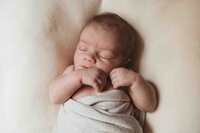 Swaddled newborn baby boy on a pillow for a lifestyle newborn session in Pittsburgh, PA