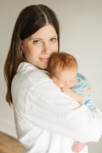 a mother holds her newborn baby on her chest and cheek