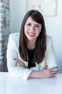 Julia Bonner, founder and president of Pierce Public Relations, smiling and leaning on a white table in a light-filled office.