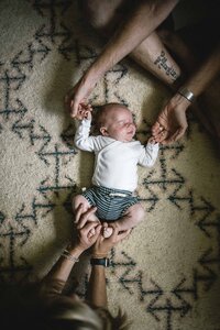 Mom and dad holding newborn on Moroccan rug