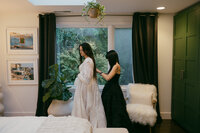 bridesemaid helping bride with her wedding dress