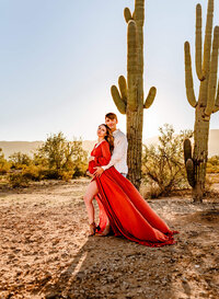 AZ dad hugging his pregnant wife next to Phoenix  saguaro cactus for photography session