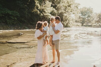 family of 4 standing in a creek