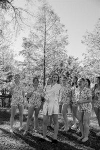 Bride popping champagne surrounded by bridesmaids in matching pajamas during wedding morning celebration at Cypress Creek Farmhouse in Astatula, Florida.