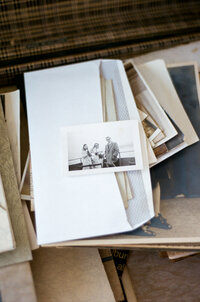 a pile of old film photographs inside of a suitcase. 