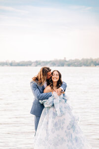 Couple standing by the lake snuggled together romantically on their wedding day