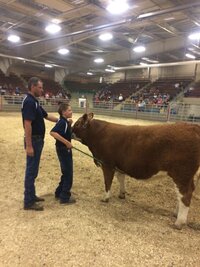 Rylan, a former patient of Lethbridge Orthotics, with his cow in a brown field.
