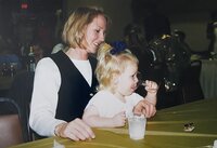 daughter sits on mom's lap at table