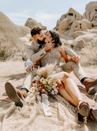 bride and groom sit in desert