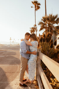 A couple standing forehead to forehead while the sun sets over Newport Beach. 