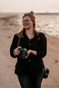 Tessa Baas met een camera in haar hand op het strand