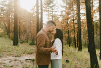 man and woman kissing in forest