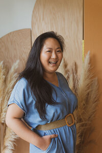 A woman smiling in front of a wooden and pampas grass background
