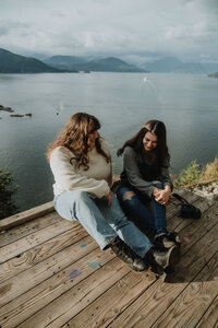 two girls sitting on a lookout in vancouver