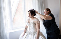 Casey, Founder of Most Valuable Bridesmaid behind the scenes at wedding with New York Bride helping to attach bridal veil.
