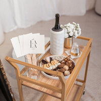 The Bubbly & Bites bridal appointment experience cart that has a sweet and savory board of goodies, with rating signs, flowers and bottle of champagne at our bridal stage.