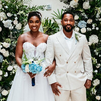 Bride and groom posing outdoors under a floral archway, featured in Ealisha and Ladarrius’s review of White House Wedding Photography.