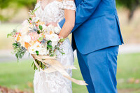 Details of newlyweds hugging and holding a large white and pink bouquet