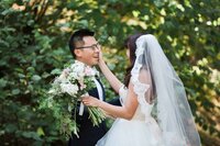 Bride and groom crying during their vows, while standing outside surrounded by pine trees.