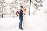 portrait of bride and groom smiling in the snow during a snowstorm in Lake Tahoe
