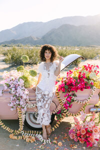 Bride poses with luxurious florals and classic car