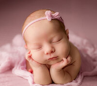 sleeping newborn baby boy wrapped in. green with little hands sticking out