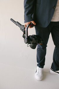 A man holds a camera in his hands, prepared to document the scene before him with enthusiasm.