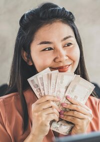 Close up image of a woman hold a bunch of dollar bills