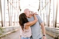husband and wife kissing on bridge