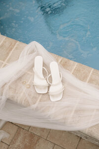 A close up of a bride's shoes on her wedding day. She's walking away from the camera with her groom next to her.