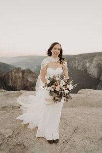 a Bride holding her flower bouquet in front of a mountain view
