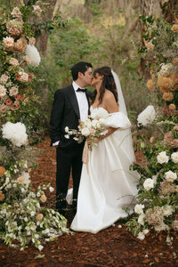 Bride and groom surrounded by romantic florals at an outdoor ceremony, planned by Northeast Florida wedding planner The Eventful Gals.