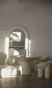 Modern white dining room with curved chairs, a round table, and large arched mirror