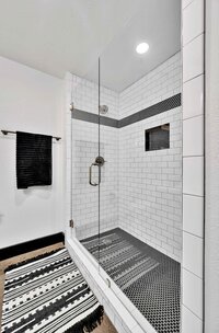 Walk-in shower with subway tile in this Master bedroom with exposed brick and urban fixtures in this one-bedroom, one-bathroom condo in the historic Behrens building in downtown Waco, TX