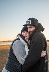 Couple lovingly holding each other while facing each other, trying to stay warm during a couples photography session in Southern Maine.