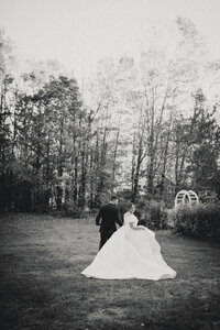 Bride and groom holding hands running through a garden and looking back at the camera. 