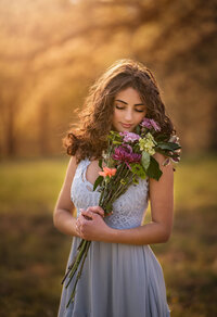 A beautiful young girl with a bouquet of flowers  in the sunlight