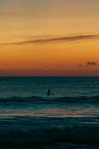 Sunset view of the ocean with a surfer in the distance