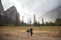 Newlyweds run through the rain on day two of their adventure elopement in Yosemite