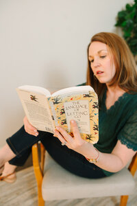 Lindsay playfully sitting in a chair with a book in her hand