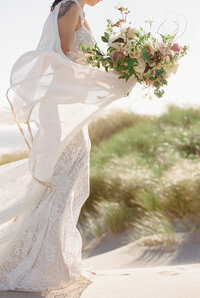 a bride in a wind swept wedding dress holding a bouquet in oregon