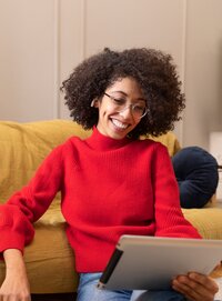 Smiling woman on a tablet during a virtual session, reflecting accessible, flexible online somatic therapy offered throughout New York state.