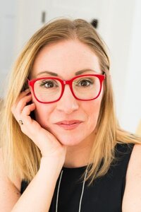 A woman with red glasses and a black top, representing Rachel Kotack Psychotherapy.