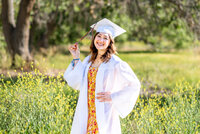 Girl in white cap and gown holding her tassel