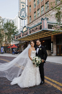 A photo of a bride and groom posing for a photo in the street