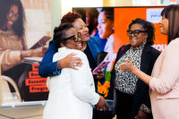 Women smiling and hugging each other at a conference