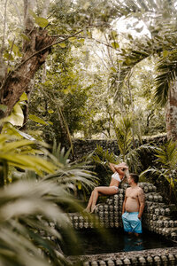 Husband and wife in Tulum Mexico with water falling onto brides head from a small waterfall