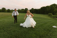 Close-up of maid of honor helping bride with her train blowing in the wind on a sunny day, captured in a film photo.