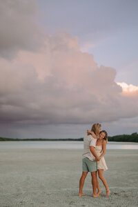 man and woman kissing while standing on the beach