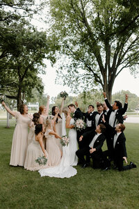 bride and groom kissing as wedding party celebrates